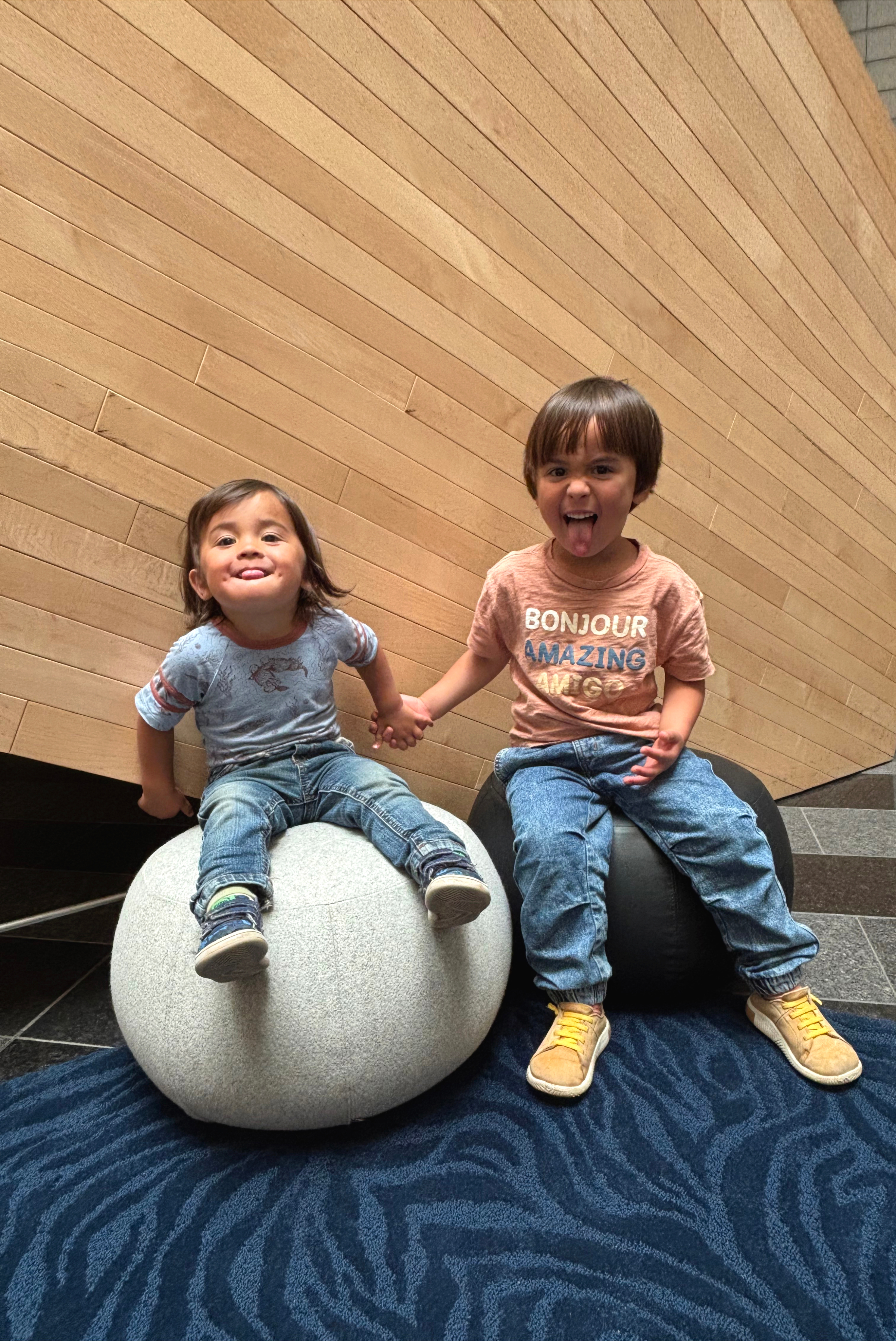 Two children ages 2 and 5, sitting on round chairs inside the SFMOMA
