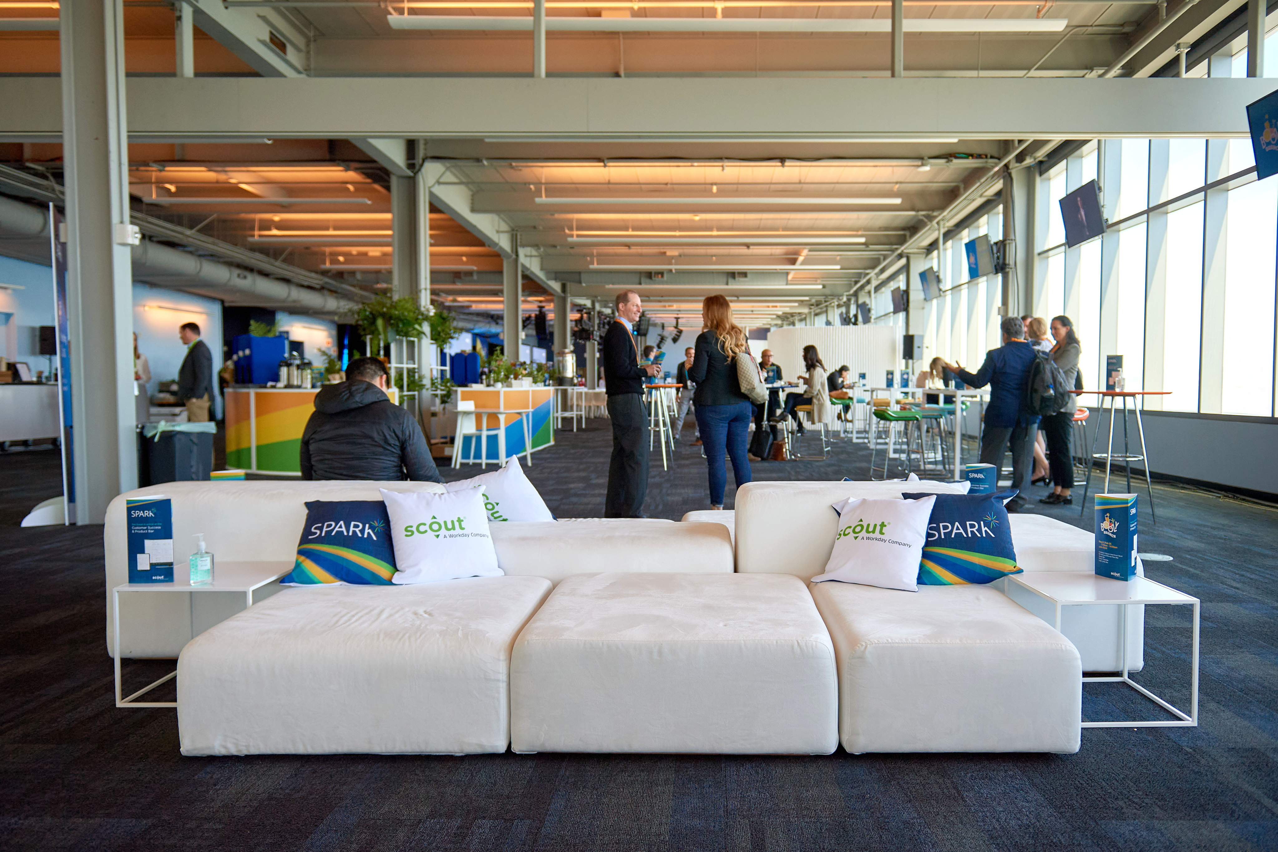 A view of the networking area at the Spark Customer Event, people, tables and furniture for sitting